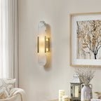 Clérachic sconce lit on a cream wall above a console of candles, a glass lantern and a stoneware jug