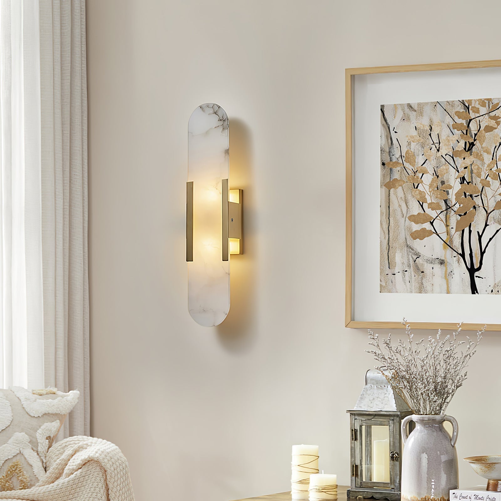 Clérachic sconce lit on a cream wall above a console of candles, a glass lantern and a stoneware jug