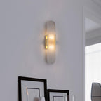 Clérachic sconce lit on a soft white wall above framed prints leaning against the surface below