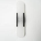 The Clérachic sconce unlit with black bars, the grey veining of the alabaster clear against a white wall