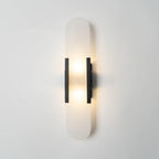 The Clérachic sconce lit head-on in black, both bulbs visible through the translucent stone capsule