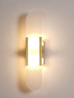The Clérachic sconce close up and fully lit, brass bars framing the bright alabaster against a cream wall