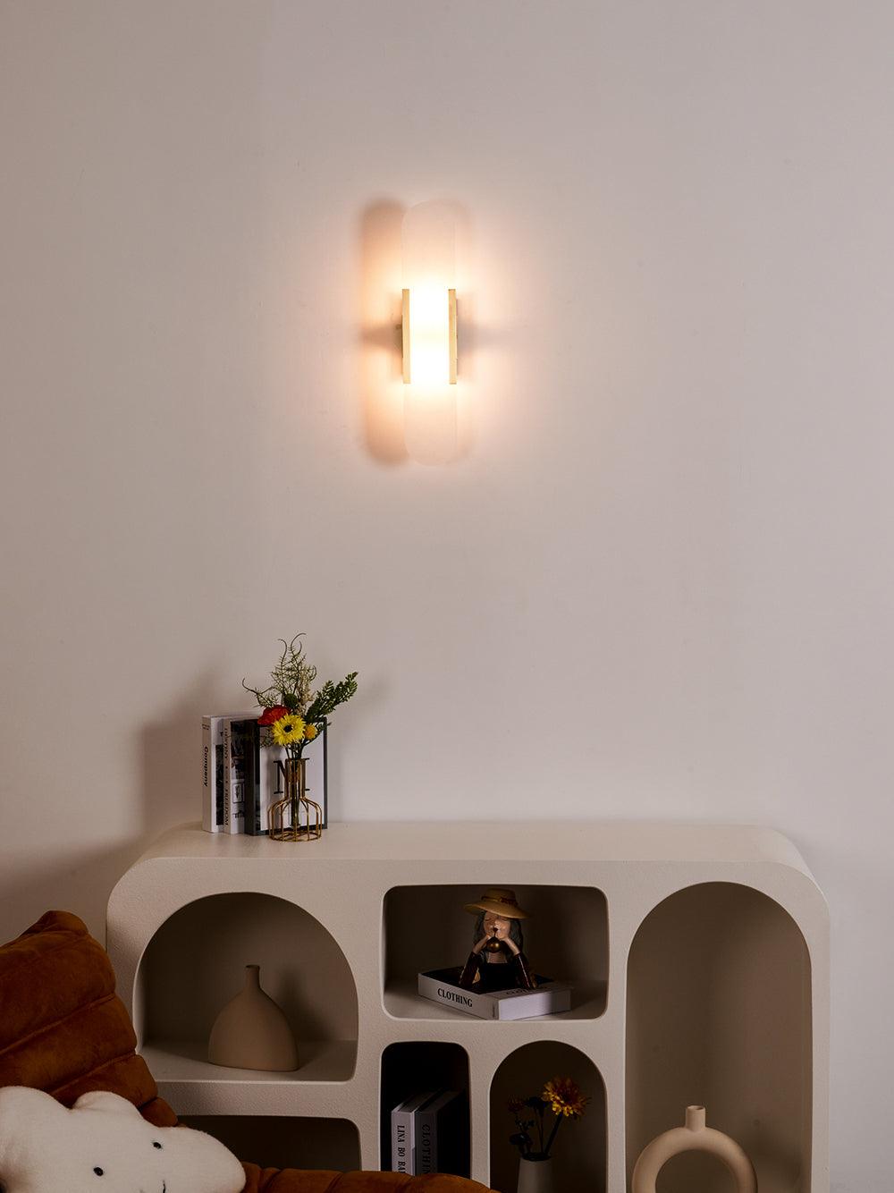 Clérachic sconce lit above a white arched shelving unit with a rust cushion and cloud pillow below