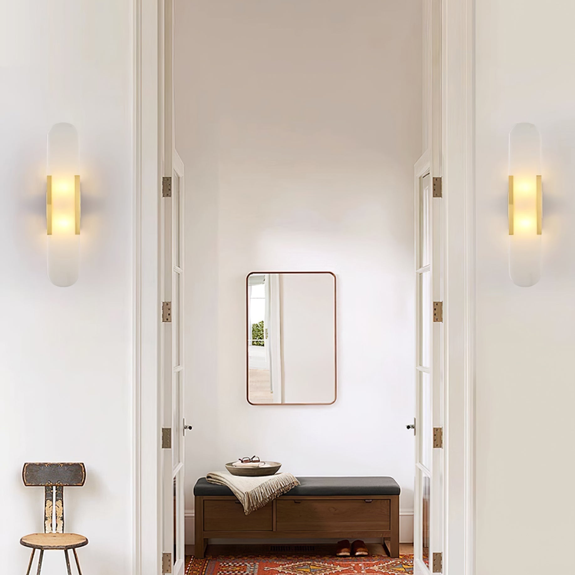 Clérachic sconces mounted either side of a doorway leading to a bench, mirror and red patterned rug