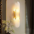 The Clérachic sconce lit beside a gold fretwork screen with a maple branch arranged in front