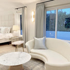 Clérachic sconce lit on a white wall in a bright lounge with a curved boucle sofa and marble table