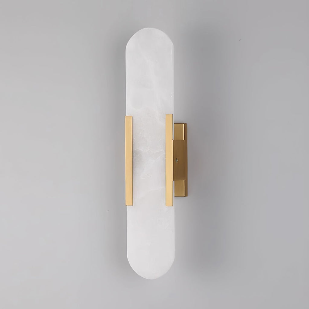The Clérachic sconce unlit head-on in brass, the hardware sitting low on the tall stone capsule