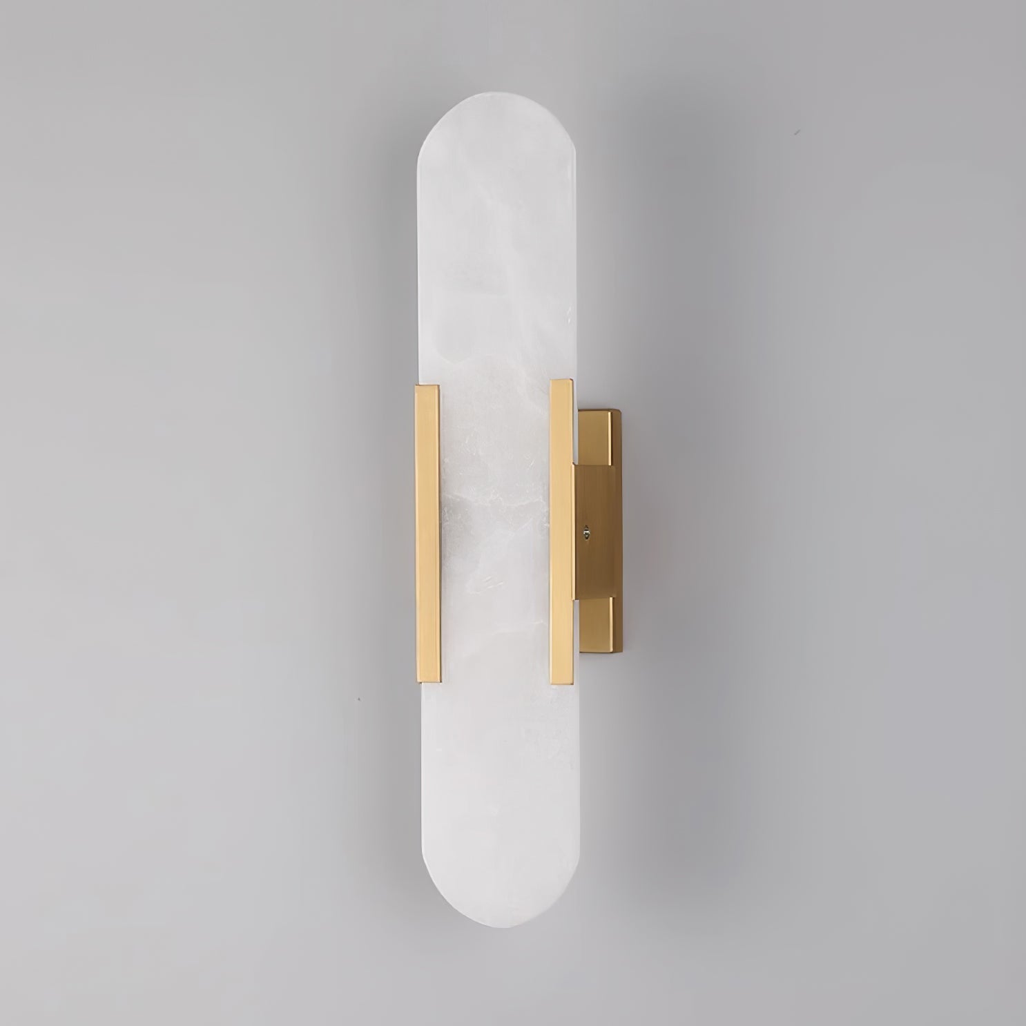 The Clérachic sconce unlit head-on in brass, the hardware sitting low on the tall stone capsule