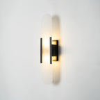 Clérachic sconce lit at a three-quarter angle, the black backplate stepped off the white wall