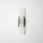 The Clérachic sconce unlit in black, shown flat-on so the full capsule proportions read clearly