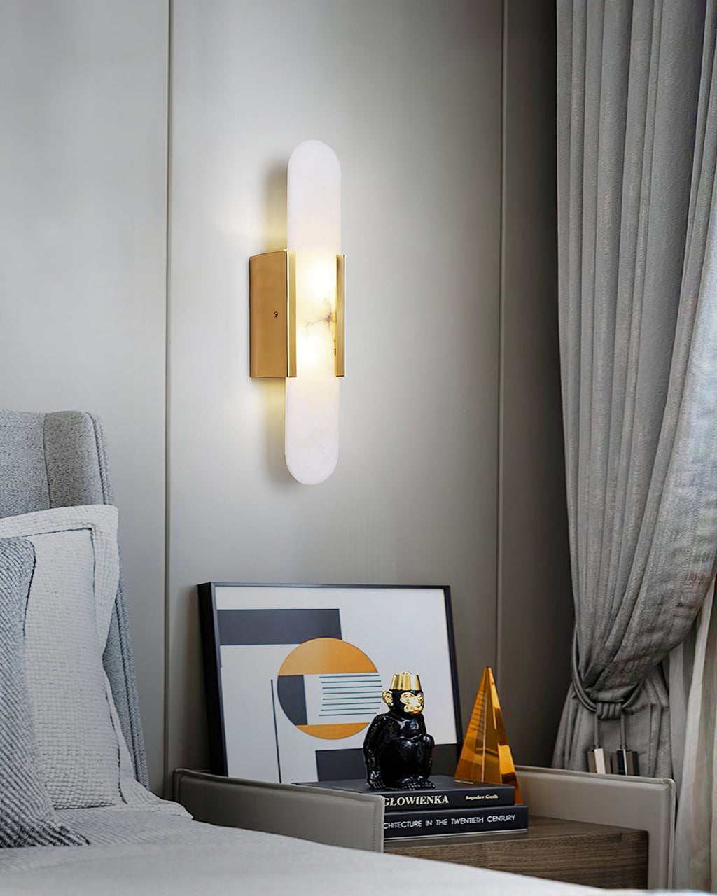 The Clérachic sconce lit on a grey panelled bedroom wall beside an armchair and a styled console