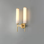 Clérachic Olrinyra twin in brass with both cylinders lit, warm light washing up the wall behind them.