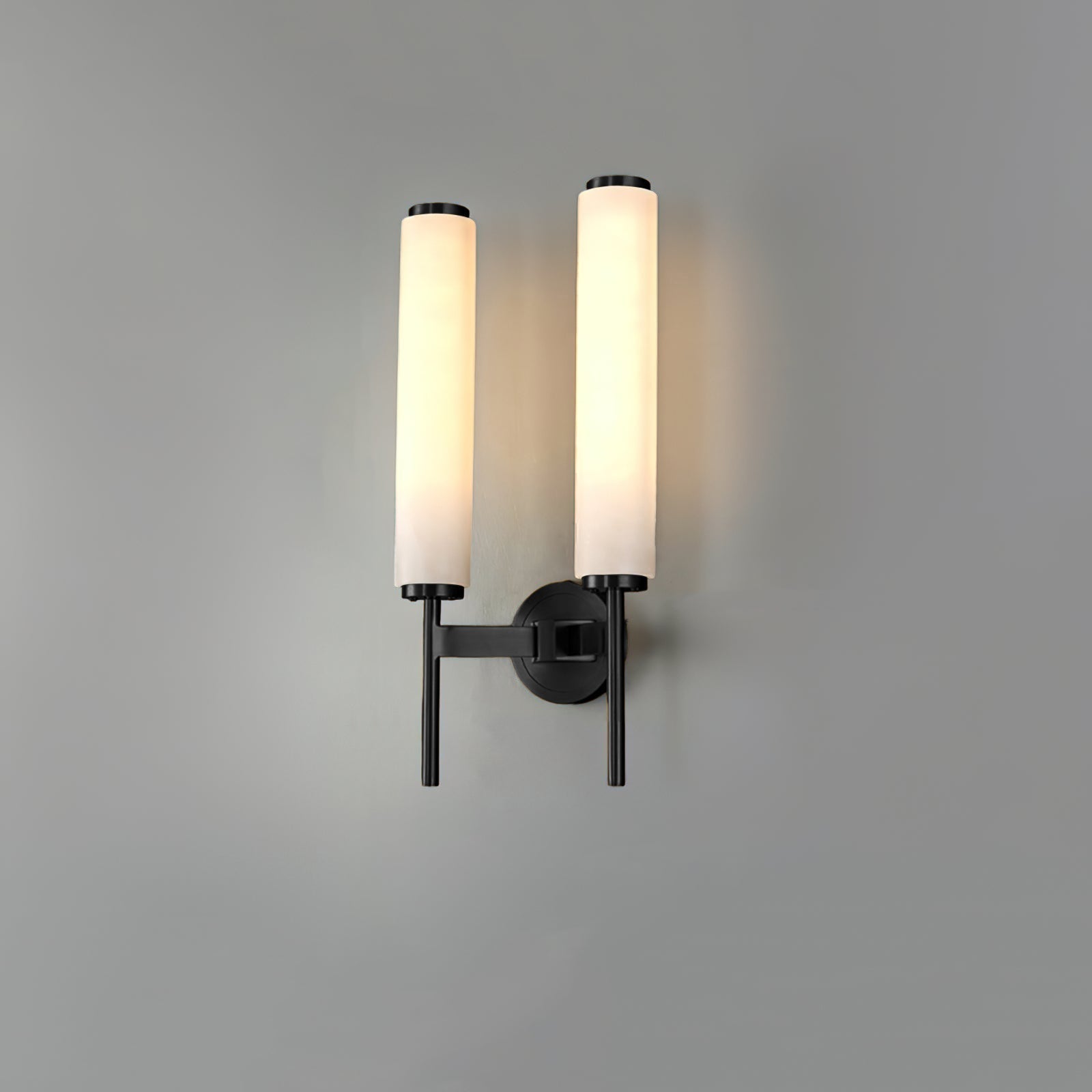 The Clérachic Olrinyra twin in black, lit, the pair of alabaster tubes glowing against a grey studio wall.