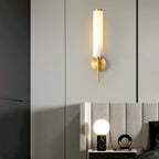 The Clérachic Olrinyra in brass lit on a panelled wall, above a bedside table set with a marble lamp.