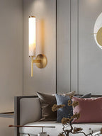 Clérachic Olrinyra in brass lit in a living room, mounted beside a low sofa dressed with layered cushions.