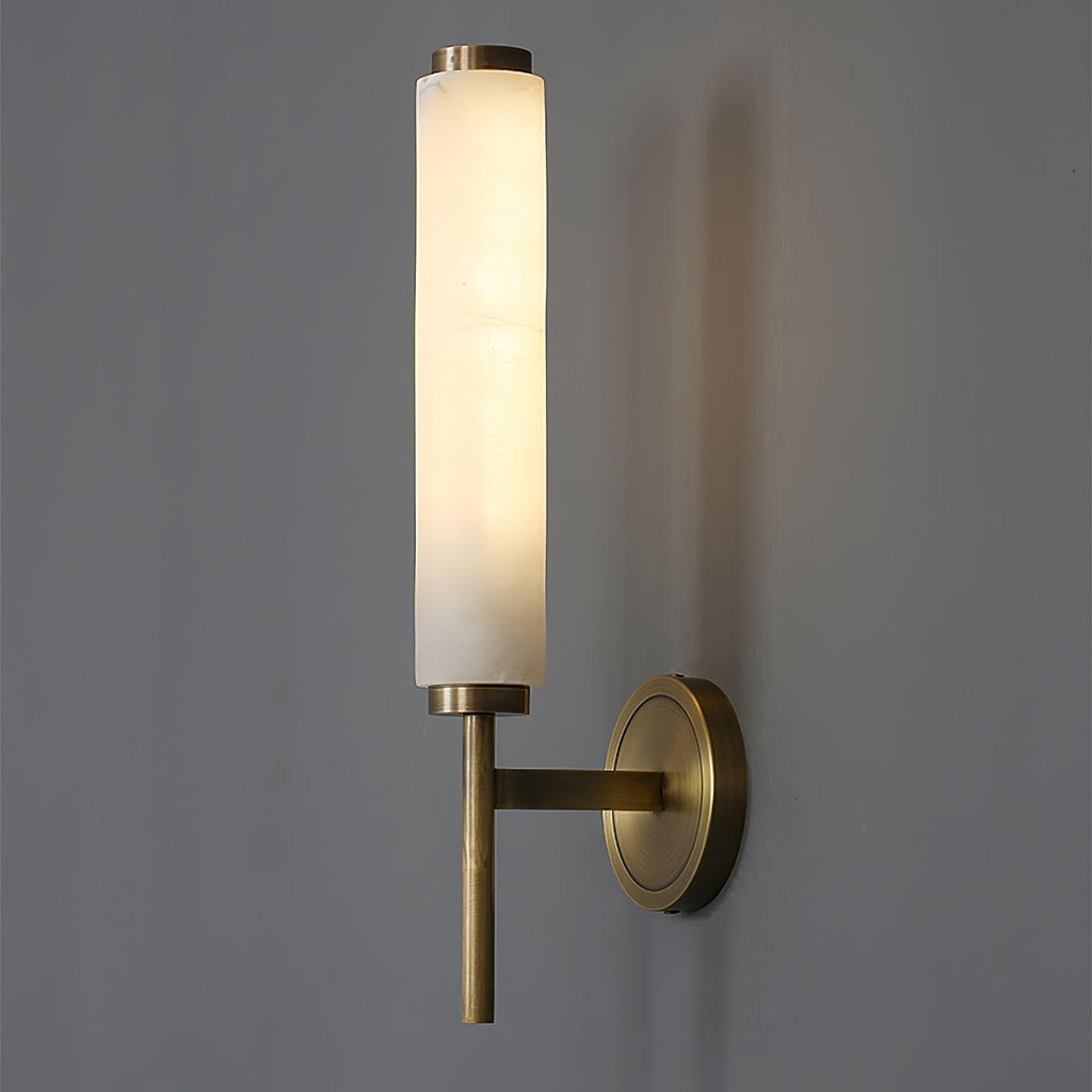 Clérachic Olrinyra in brass lit at three-quarter view, arm and tapered tail reading against a grey wall.