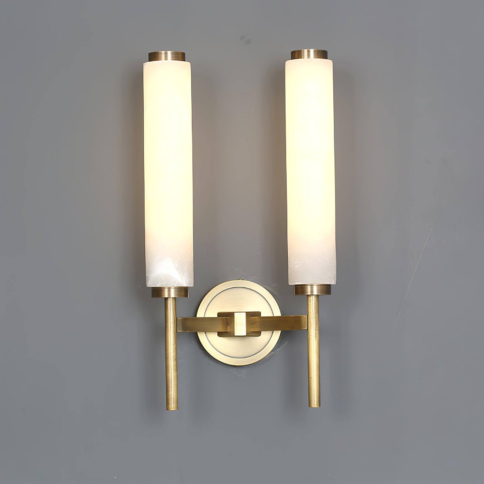 Clérachic Olrinyra twin in brass with the tubes spaced wide, both lit above the shared brass wall mount.
