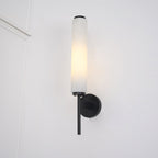 The Clérachic Olrinyra in black lit on a white wall, its dark disc and tail set against the alabaster tube.