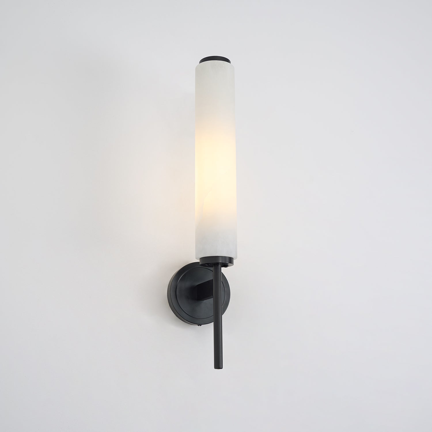 Clérachic Olrinyra in black, lit, the warm stone column contrasting with the matte black arm below it.