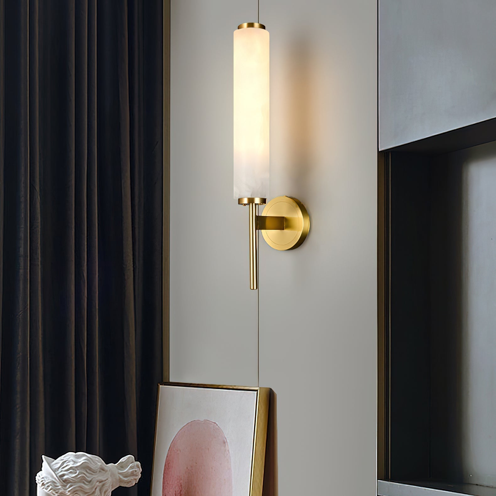 The Clérachic Olrinyra in brass lit near a dark drape, above a leaning artwork and a white plaster bust.
