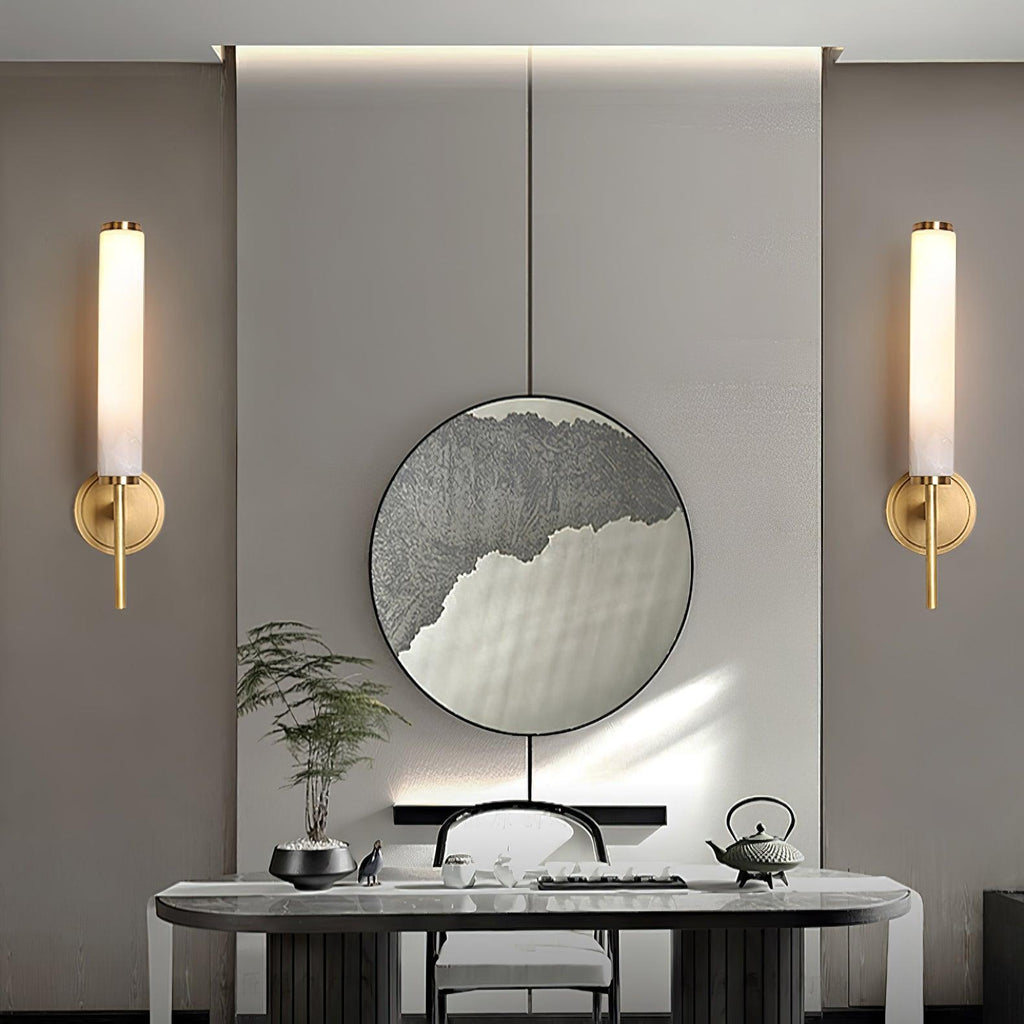 A pair of Clérachic Olrinyra sconces in brass flanking a round mirror above a marble console and tea set.