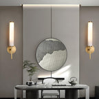 A pair of Clérachic Olrinyra sconces in brass flanking a round mirror above a marble console and tea set.