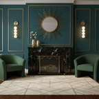 Gold Clérachic wall lights lit either side of a sunburst mirror on a deep green panelled wall, with two green armchairs below.