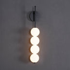Close front view of the black-finish Clérachic wall light on a charcoal wall, four lit opal balls hanging from a slim black arm.