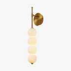 Side-on view of the gold Clérachic wall light glowing warm on a white background, showing the arm projecting from the round backplate.