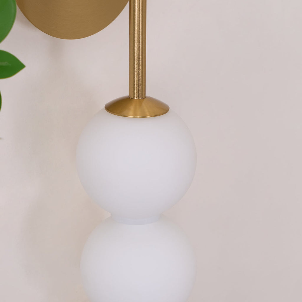 Close view of the brass arm and cone fitting where it meets the top opal ball on this Clérachic wall light.