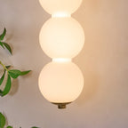 Close view of two glowing opal glass balls and the small brass cap at the base of this Clérachic wall light.