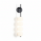 Black-finish Clérachic wall light lit on a white background, with a soft shadow of its four balls beside it.