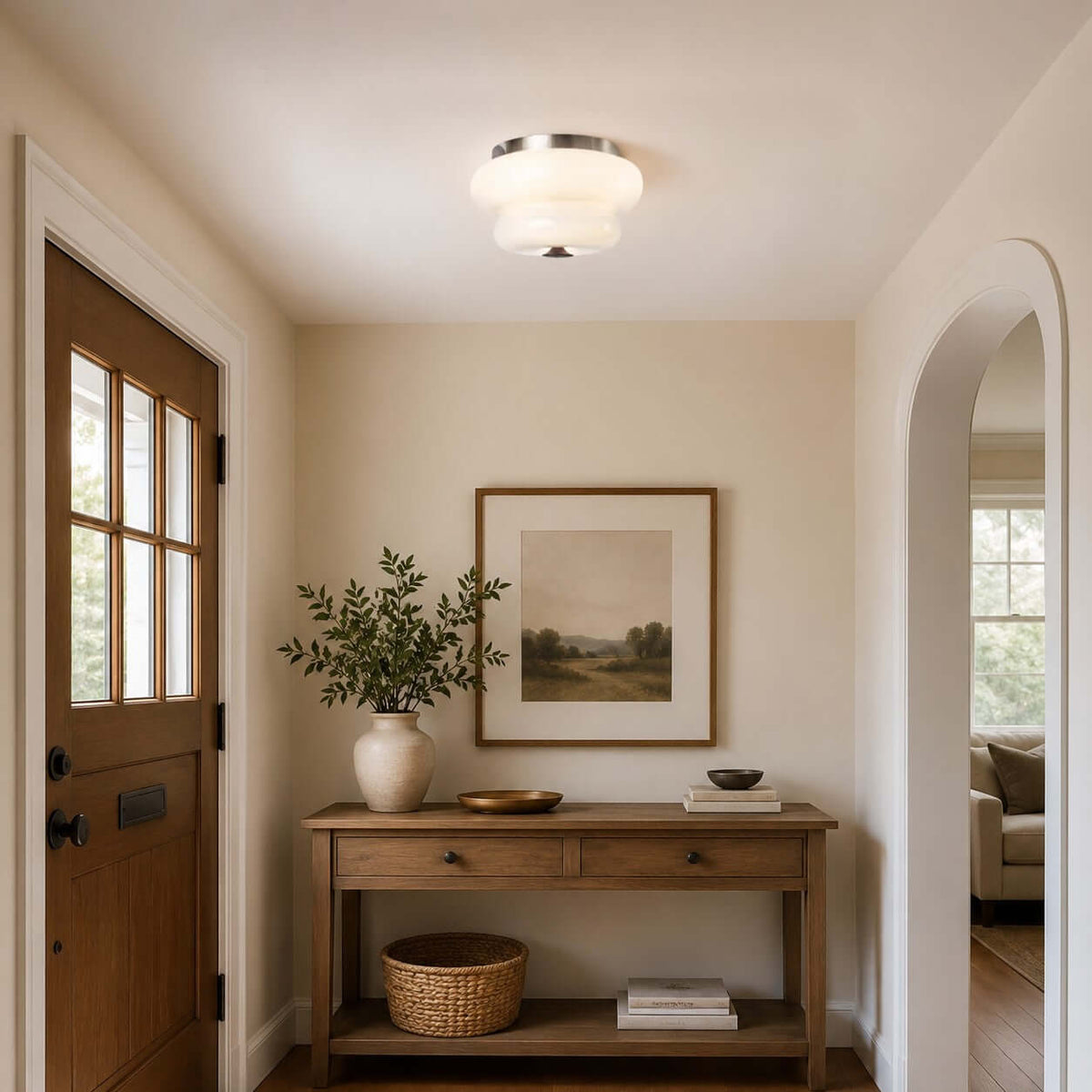 A Clérachic flush-mount light sits on the ceiling of an entrance hall with a wooden door and a console table with a vase.