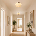 A Clérachic flush-mount light in a long, bright hallway, with a second light visible further along the ceiling.