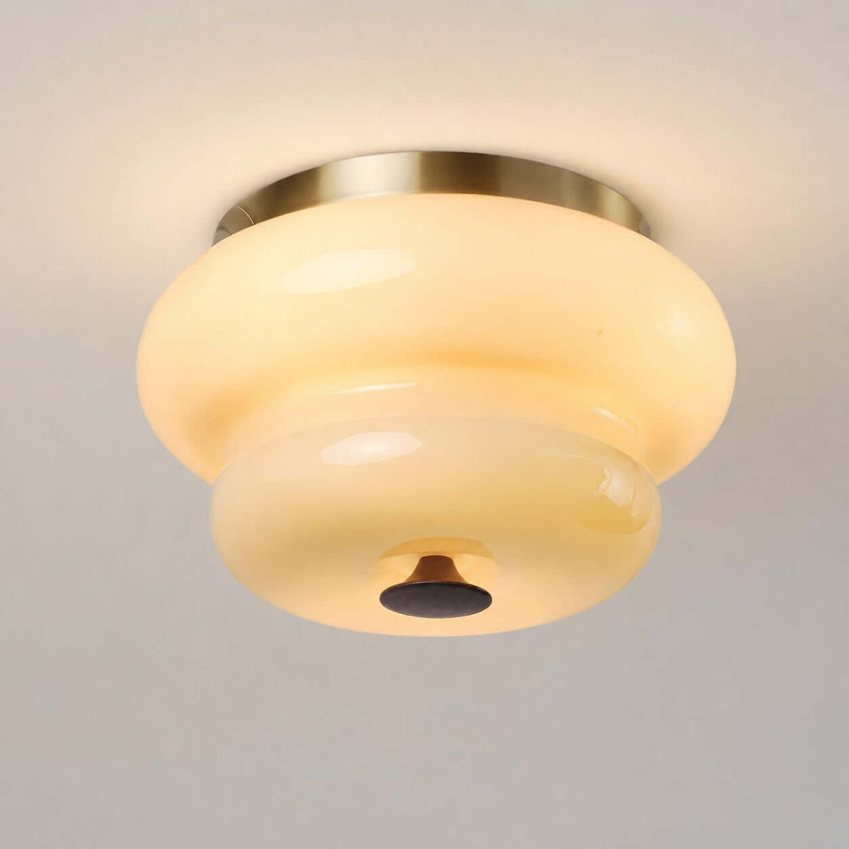 Close view from below of the cream opal glass tiers, brass ring and dark finial of this Clérachic flush-mount light.