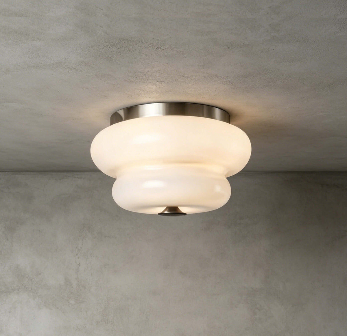 A Clérachic flush-mount light in a nickel-toned finish with a white glass shade, fixed to a grey concrete ceiling.