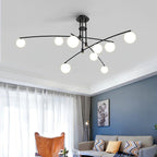 A black Clérachic globe chandelier with crossing arms in a living room with a blue wall, sheer curtains and a tan armchair.