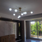 A gold Clérachic globe chandelier lit near a marble feature wall and a balcony door, with boxes still stacked below.