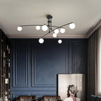 A black Clérachic globe chandelier above a navy panelled room, with brown leather chairs and a framed artwork below.