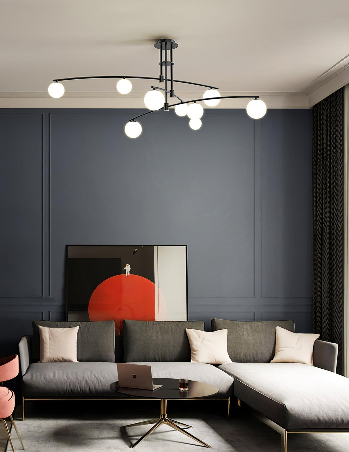 Black Clérachic chandelier hanging over a corner sofa in a room with a slate-blue wall and an orange-and-red artwork.