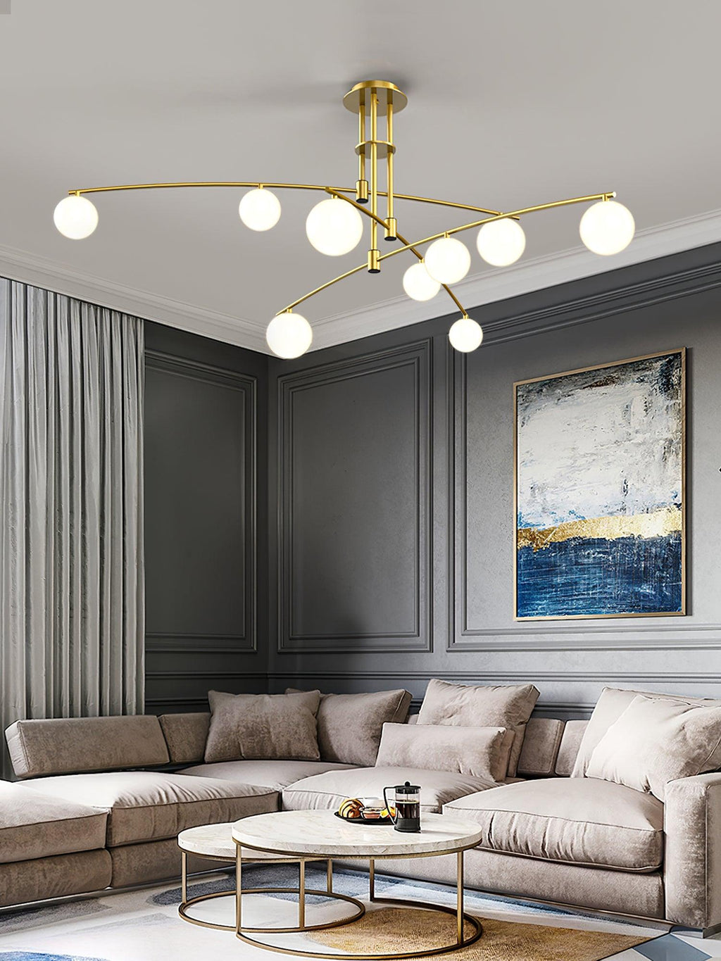 This Clérachic gold chandelier above a cream corner sofa, with a navy and gold painting on a grey panelled wall.