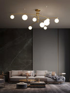 A gold Clérachic chandelier with opal globes over a grey living room with a dark stone feature wall and a low sofa.