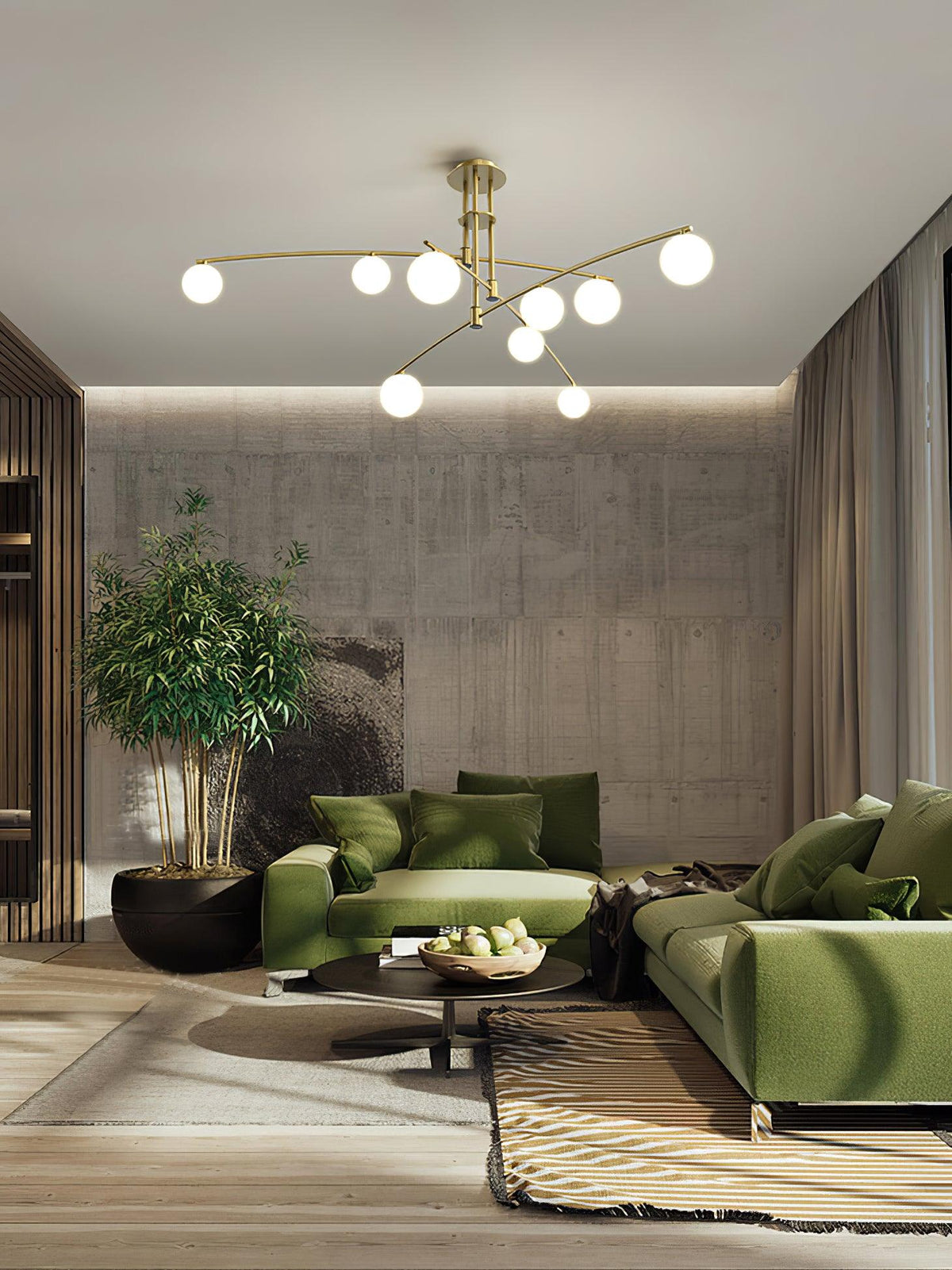 Gold Clérachic chandelier above a living room with green sofas, a concrete-look wall and a large indoor plant.