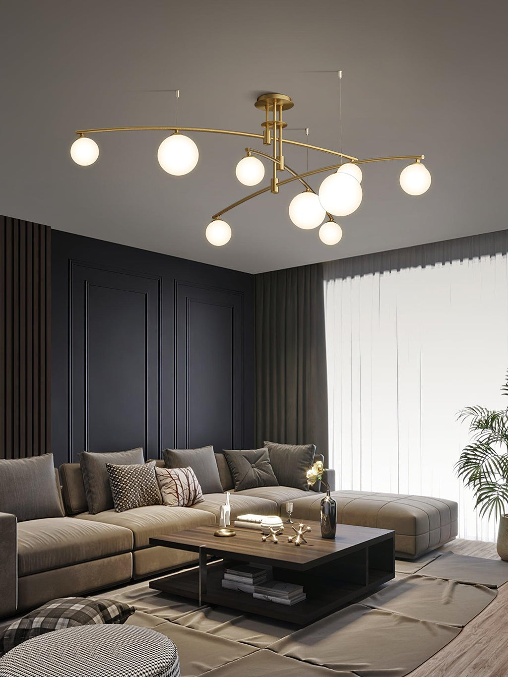 A gold Clérachic chandelier glowing above a corner sofa and a dark square coffee table, with sheer curtains to one side.
