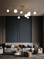 Gold Clérachic chandelier with opal globes above a cream sofa with brown cushions, against dark wood-panelled walls.