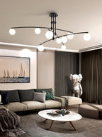Black Clérachic chandelier in a living room with a boat print, a dark green sofa and a white marble-top coffee table.