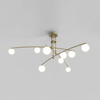 Gold Clérachic chandelier with nine opal globes on curved arms, lit, shown on a plain grey backdrop.