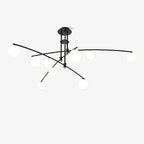 Black Clérachic chandelier seen from a low side angle, with globes of mixed sizes on sweeping arms, on a white backdrop.