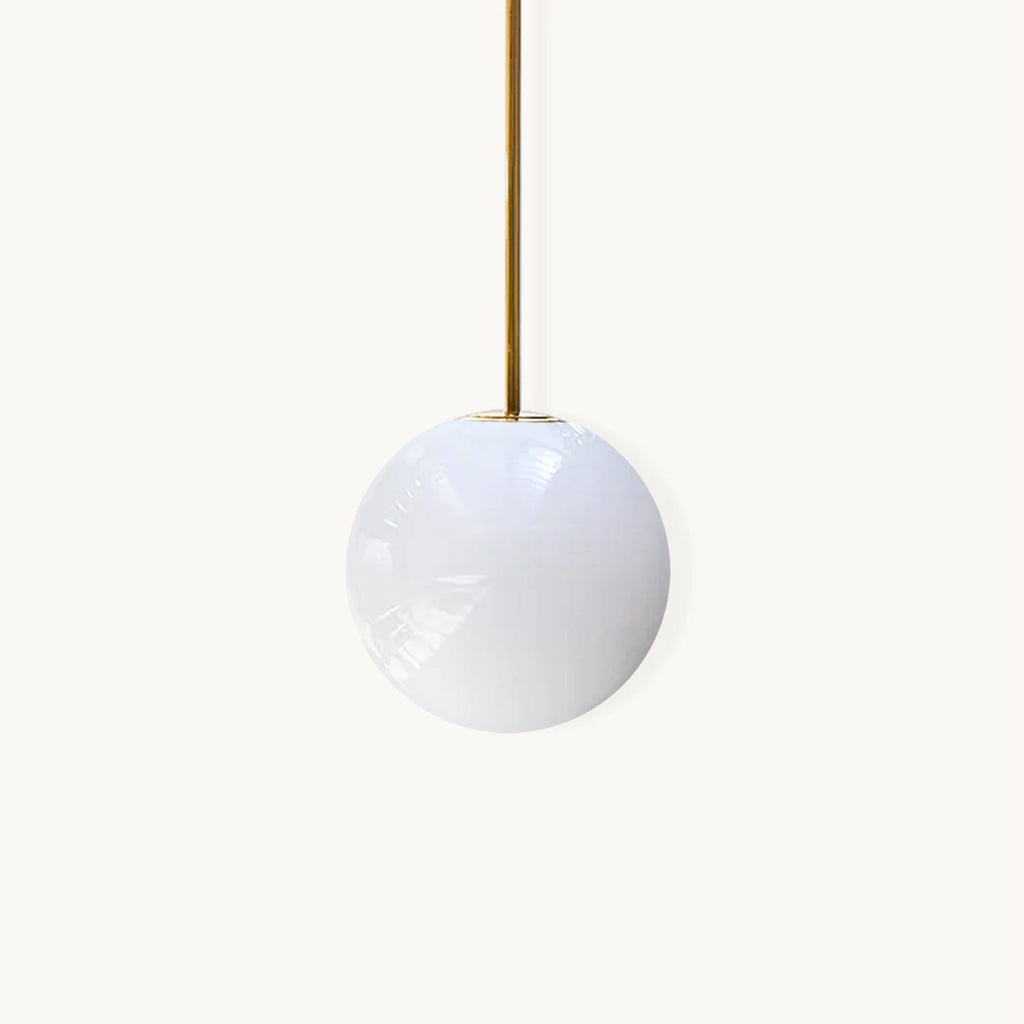 Opal glass sphere hanging from a slim brass rod, this Clérachic pendant on a plain white backdrop.