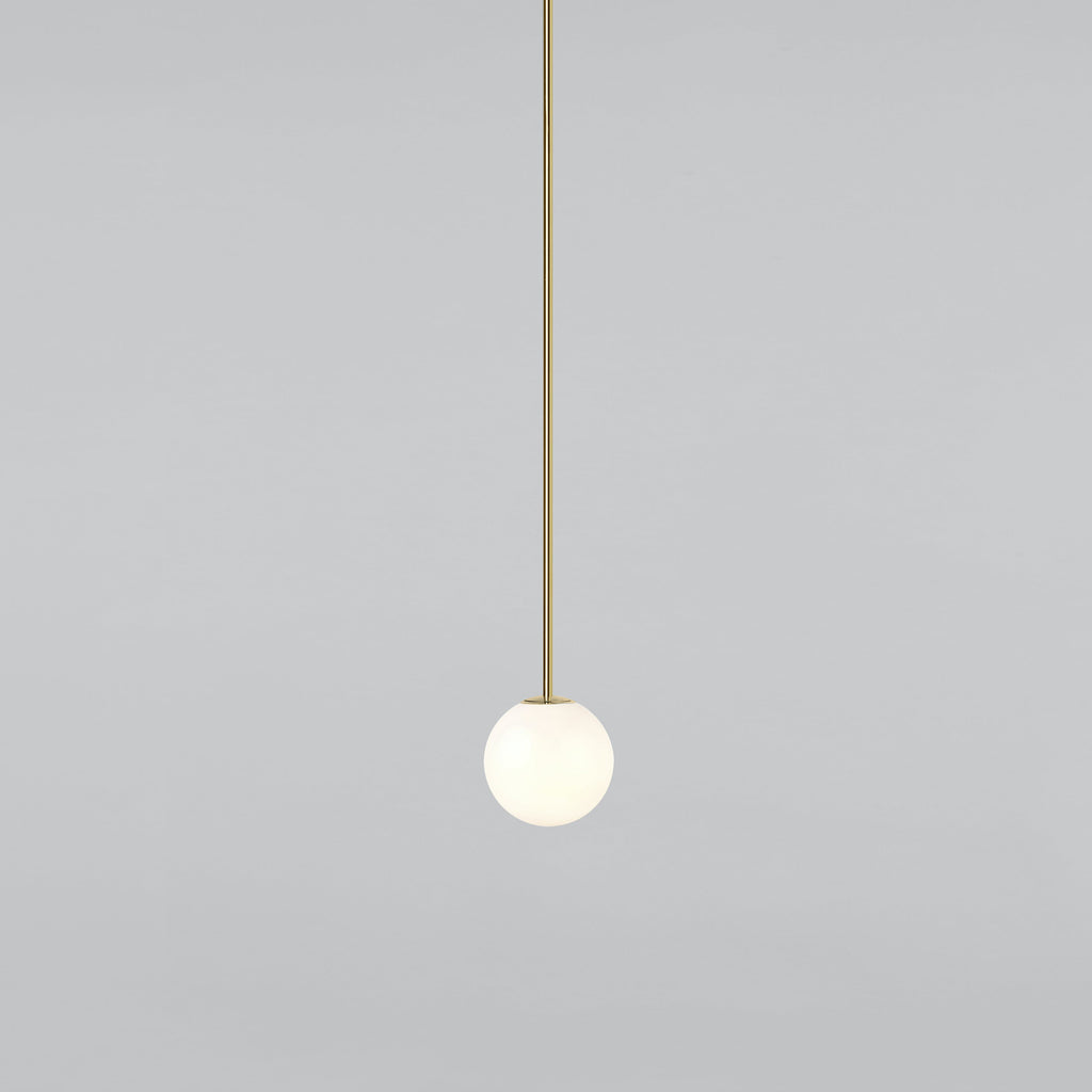 Small opal sphere on a long brass rod, this Clérachic pendant on a light grey backdrop.